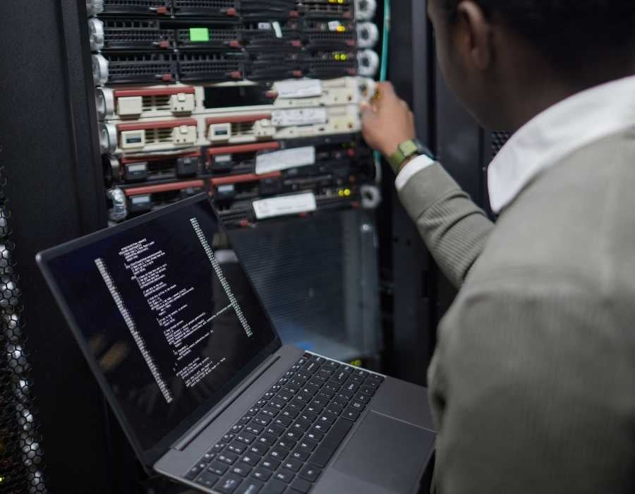 Technician working on server infrastructure with laptop in data center