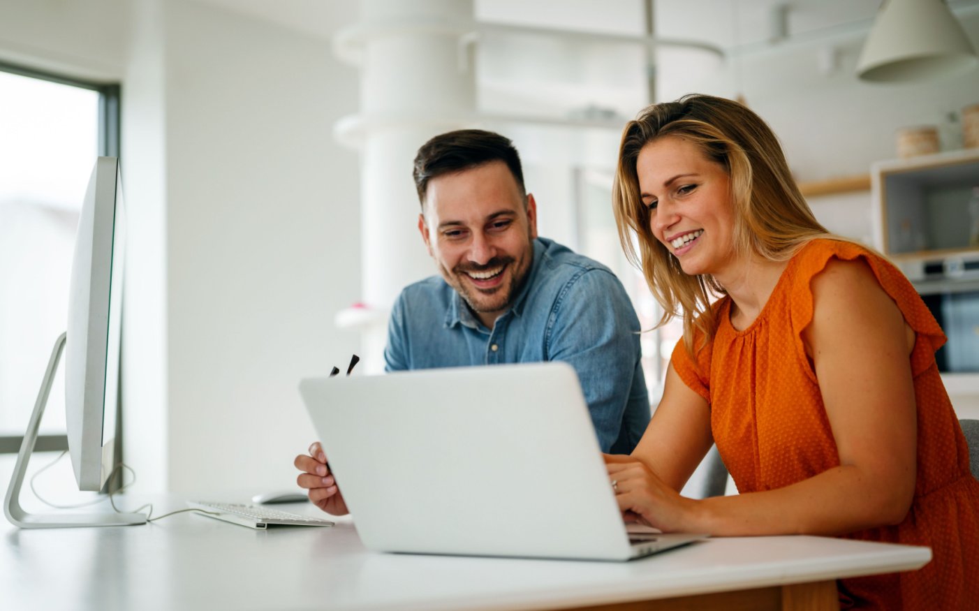 Happy, successful man and woman working together at an open laptop solving business challenges with Microsoft’s Power Platform suite of applications