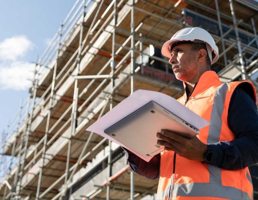 Construction professional reviewing plans on a laptop at an active job site