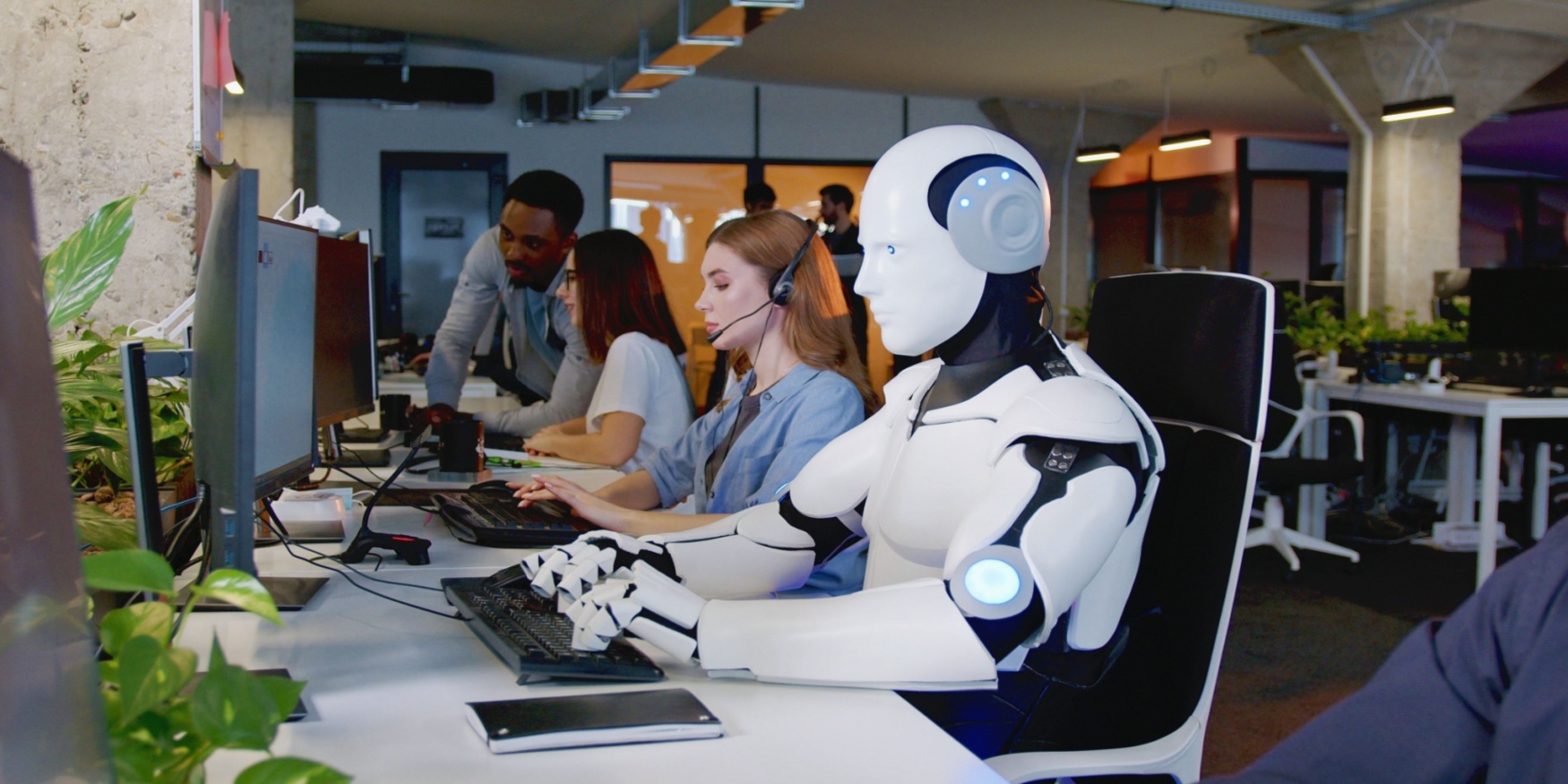 Robot working at computer on Microsoft Dynamics Copilot among people in an office